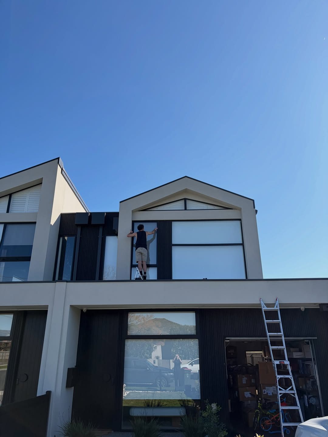 Cleaning an upper-storey window from a ladder on the garage roof