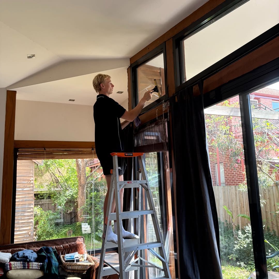 Squeegeeing a high indoor window from a step ladder
